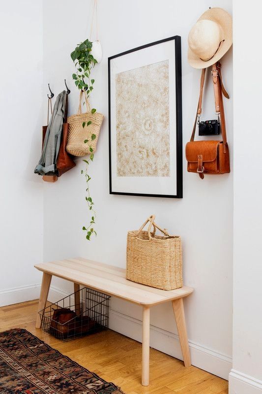 an artwork, a hanging planter with greenery and even a straw bag and hat add to the decor of the space