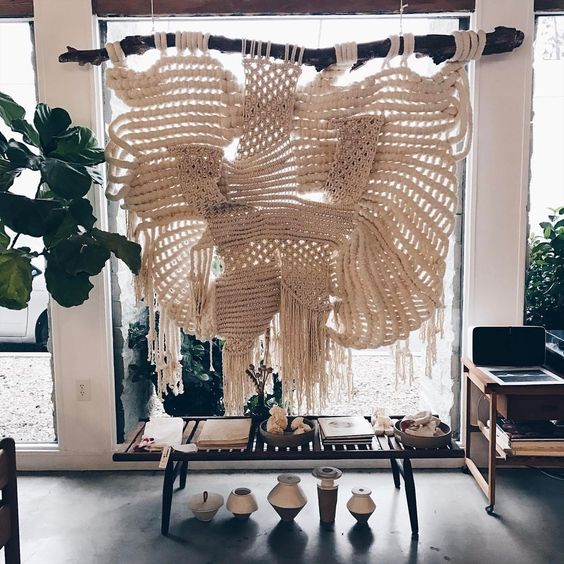 an oversized macrame hanging on a branch is a bold boho chic statement for any space