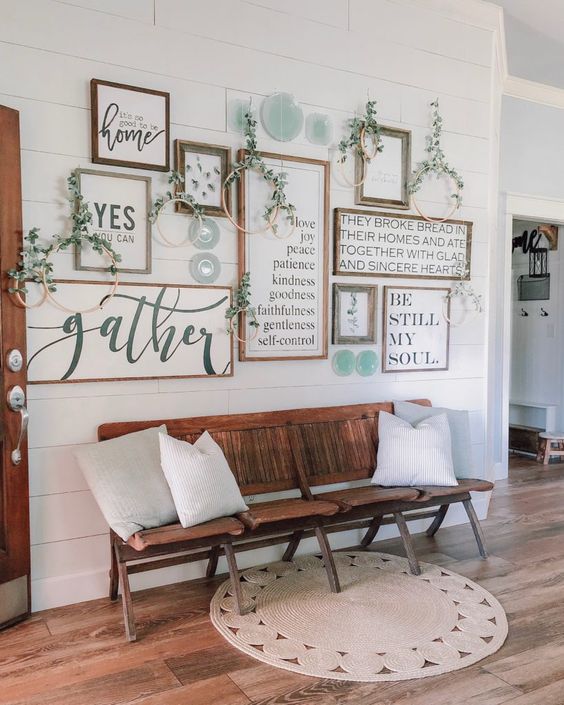 a cozy rustic gallery wall with greenery wreaths and decorative plates for a farmhouse entryway