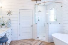 17 a light-filled farmhouse bathroom featuring white shiplap, a wooden floor, a cool chandelier and a free-standing tub