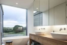 18 a neutral bathroom with a tub by a large window – nothing here distracts from the view, and light blue touches add a bit of color