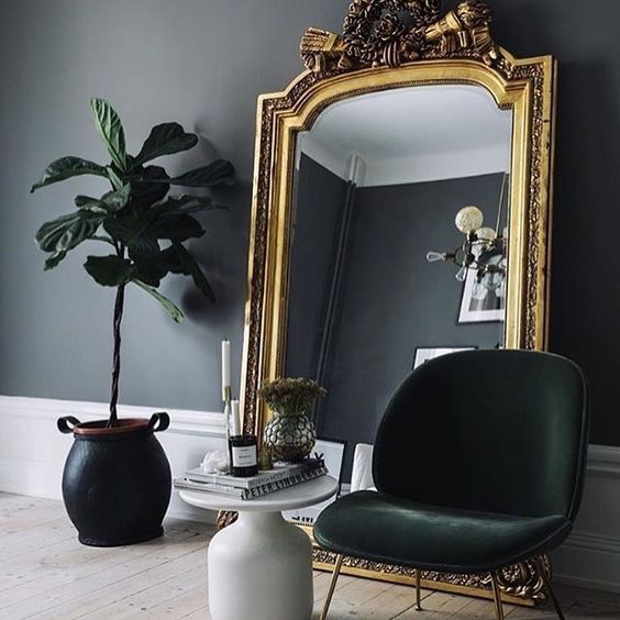 A chic moody nook with an oversized mirror in a gold frame   this mirror takes over the space and makes it wow