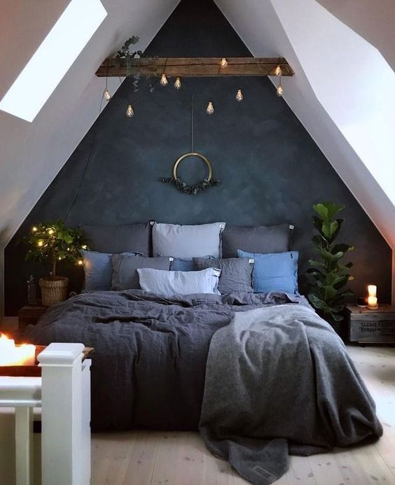 a moody attic bedroom is refreshed with candles and lights hanging over the bed itself