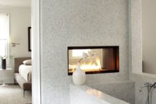 22 a contemporary bedroom and bathroom separated with a wall with a fireplace