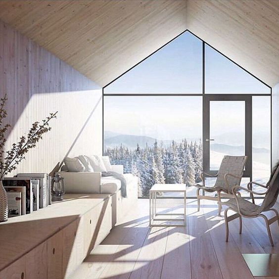 a neutral-colored chalet space with a whole glazed wall that provides the views and fills the space with natural light