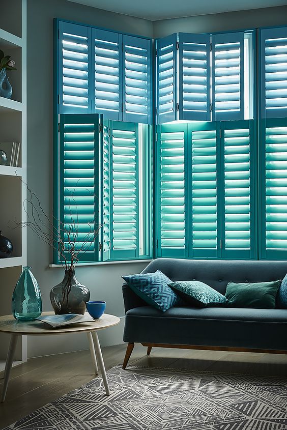 bay windows with blue plantation shutters is a chic and bold idea for a coastal or beach home