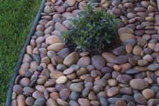 23 chic and bold pebble garden edging with little greenery bushes growing inside it for a fresher and cooler look