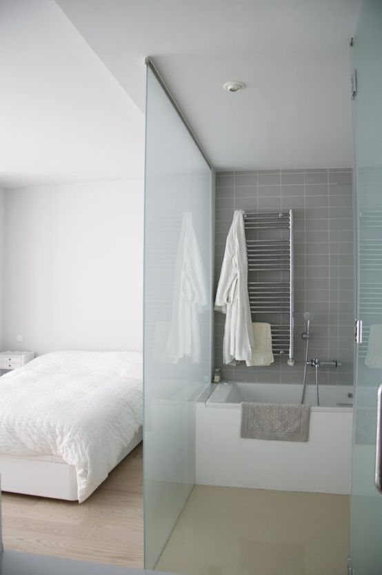 placing a bathtub into the bedroom and separating the zone with glass wall is a cool way to save the space
