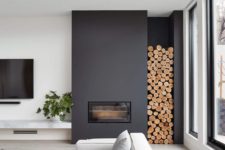 24 a contemporary living room done with a black sleek fireplace and firewood storage plus a black chandelier
