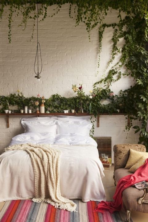 an open shelf with potted greenery and soem vines climbing up the wall is a great idea for a boho bedroom