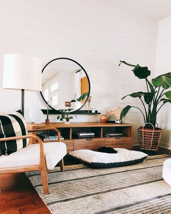 an airy boho chic living room with white shiplap walls, rattan furniture and many potted plants