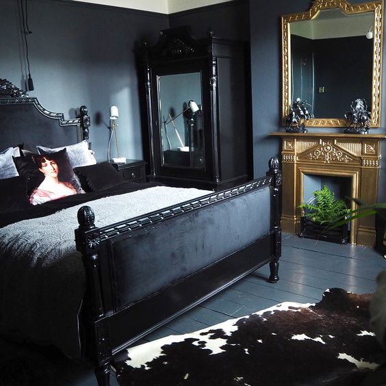 a dark moody bedroom with a couple of mirrors in heavy and carved frames for more light and more chic