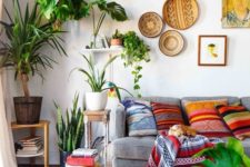 26 decorative baskets on the wall, many potted plants, colorful printed pillows and a blanket make up a cool boho space
