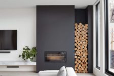 27 a minimalist black fireplace with firewood storage by it brings coziness to the space