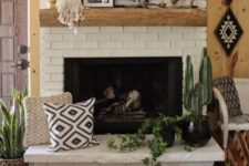 28 a brick clad fireplace with a wooden mantel, potted plants, pillows and artworks for a boho living room