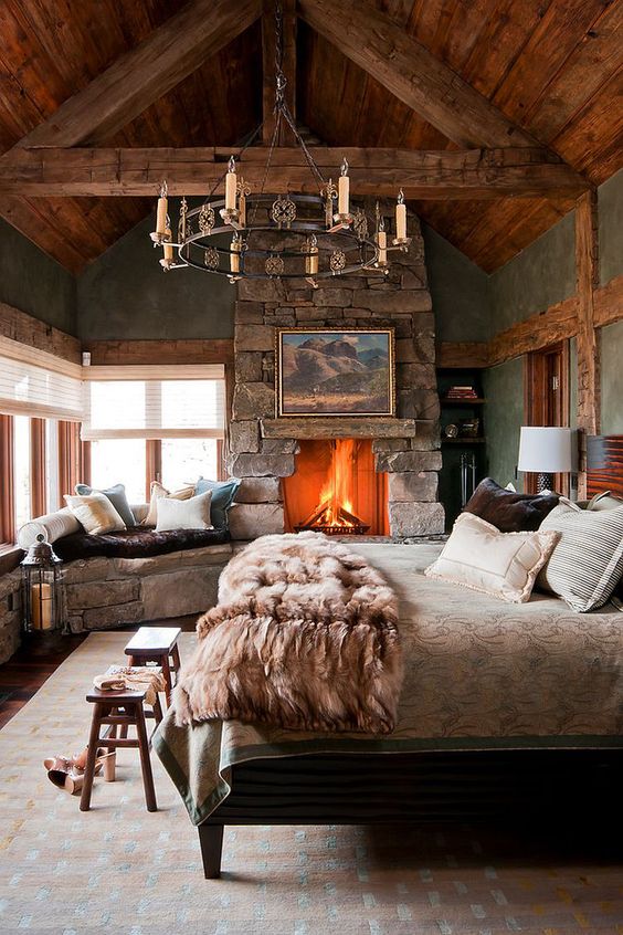 a cabin bedroom with a large stone clad fireplace that really warms up the space and makes it wow