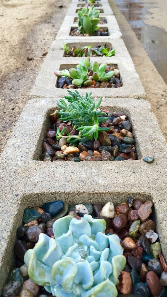 sunken cinder blocks used as planters for succulents and pebbles is a bold modern idea