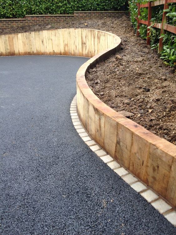 A tall wooden border for the raised garden bed and asphalt gardne pathways for an ultra modern look