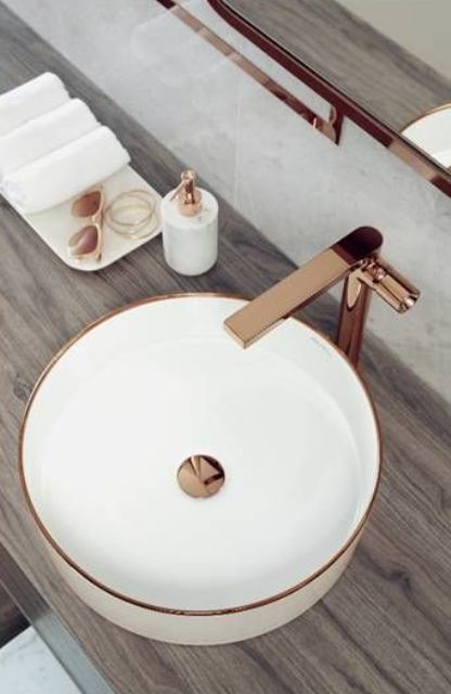 a chic round vessel sink with a copper rim and center plus a matching faucet is a beautiful and elegant option