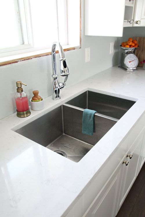 a contemporary undermount sink with two parts installed into a white stone countertop is ideal for a modern farmhouse kitchen