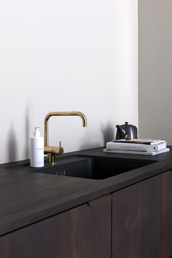 a dark cabinet with an undermount sink and a brass faucet is a chic idea that guarantees a sleek look