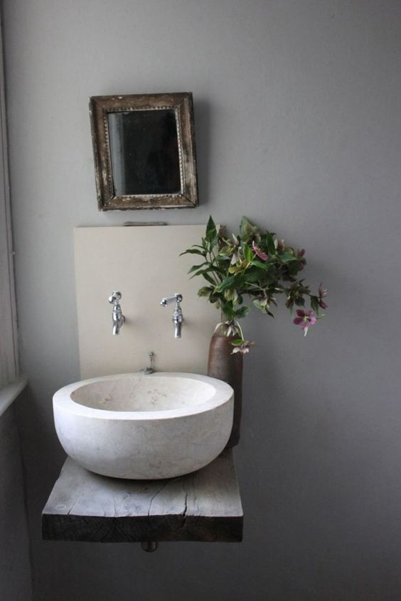 A large white stone vessel sink on a wall mounted dough wood vanity is a cool rustic item