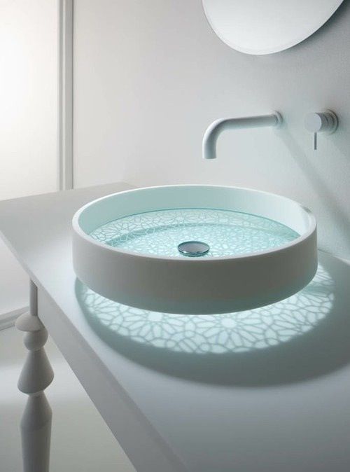 a unique sheer glass bathroom vessel sink with a beautiful painted bottom and light that comes through it