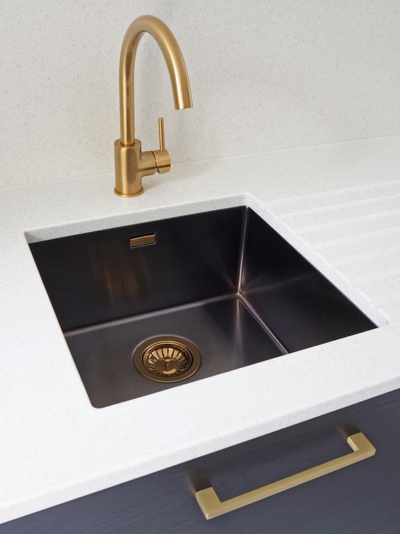 a white and navy vanity with a black undermount sink and brass and copper touches for a refined feel