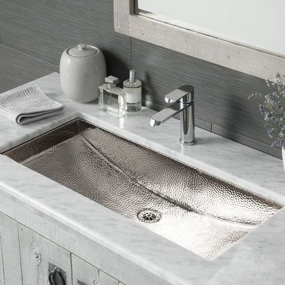 a white stone countertop and a polished hammered nickel sink for a neutral and fresh look in your bathroom