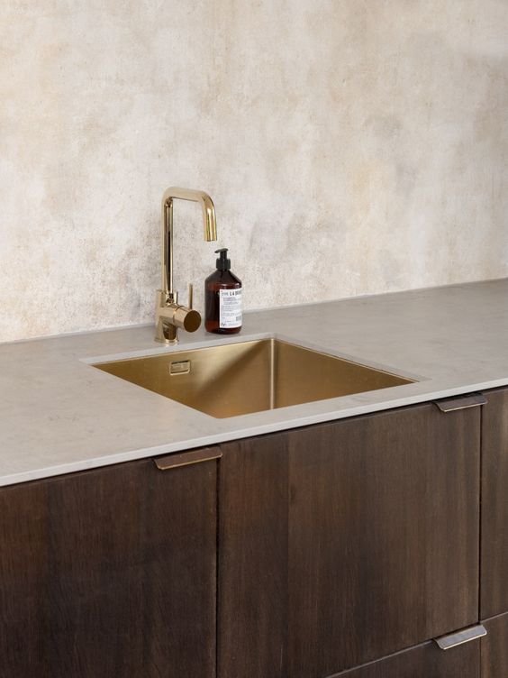 give your kitchen a warm look with dark cabinets, a neutral countertop and a gold sink plus a gold faucet
