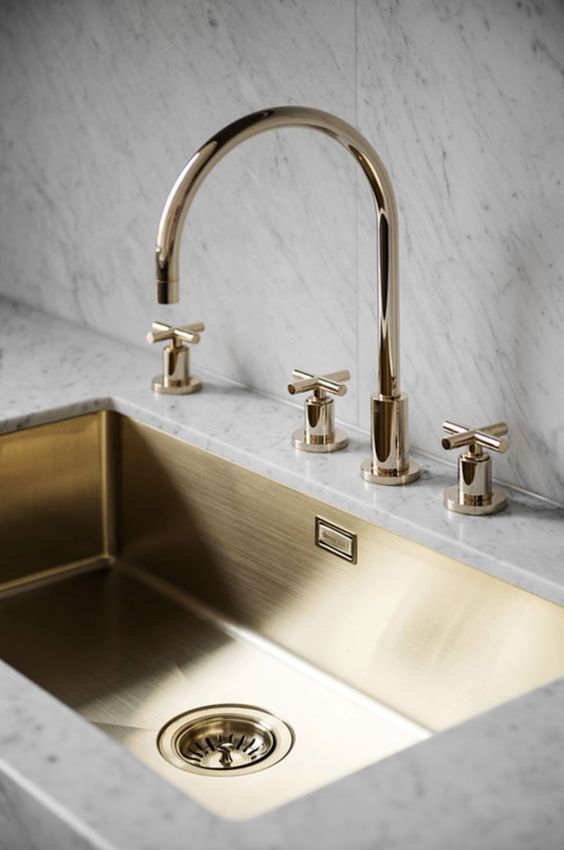 marble tiles and countertops plus a gold rectangurlar sink and gold fixtures is a touch of luxury in the space