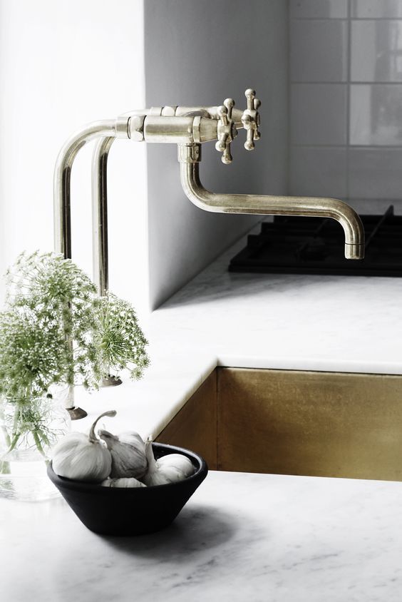 white stone countertops plus a gold undermount sink and a unique vintage faucet  for a touch of refined chic