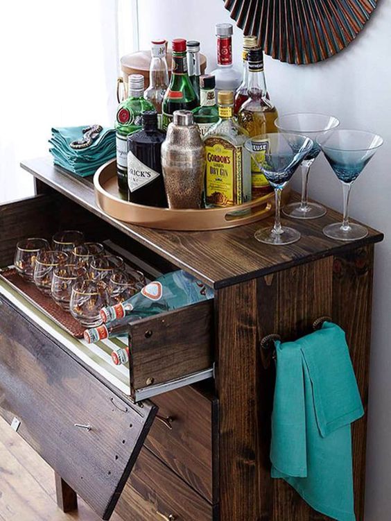 a dark stained IKEA Tarva dresser with a pullout drawer for stashing glasses and bottles is a chic rustic bar idea