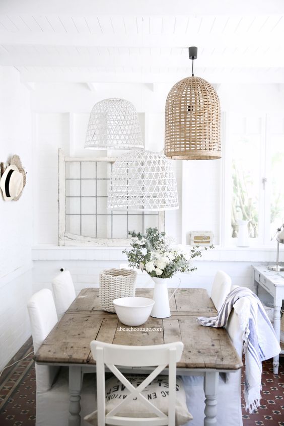 A beautiful dining space in white and neutrals and with several painted and non painted wicker lampshades over it