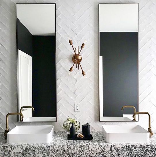 a bold art deco bathroom with white skinny tiles clad in a chevron pattern and a terrazzo floating vanity