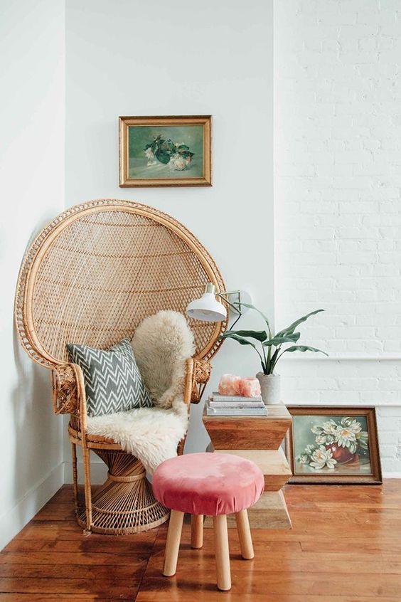 a peacock chair styled with faux fur, a pillow and a coral upholstered stool plus a side table create a gorgeous rest nook
