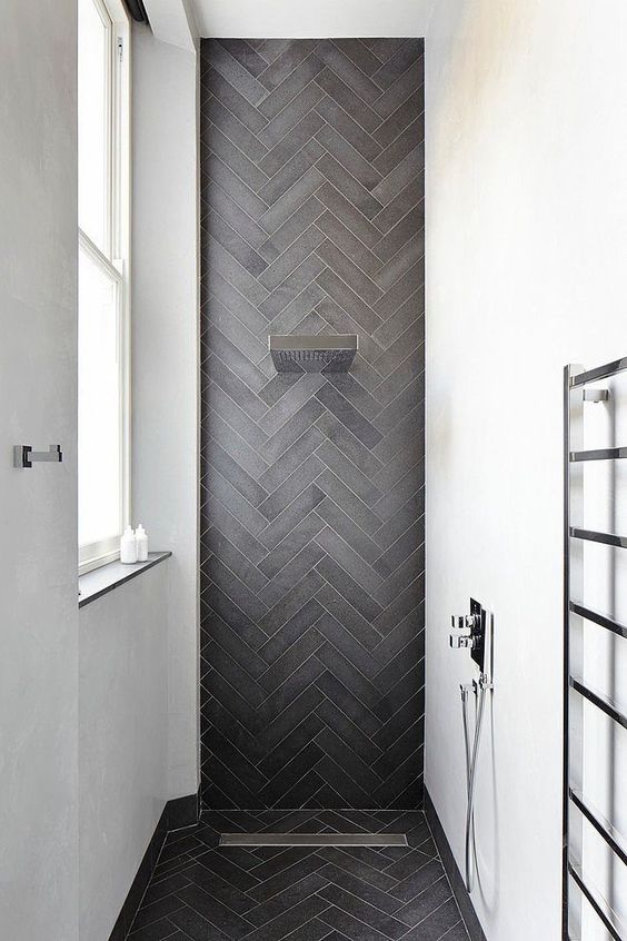 a chic contemporary shower space with white walls and an accent graphite grey skinny tiles clad in a chevron pattern and extended to the floor