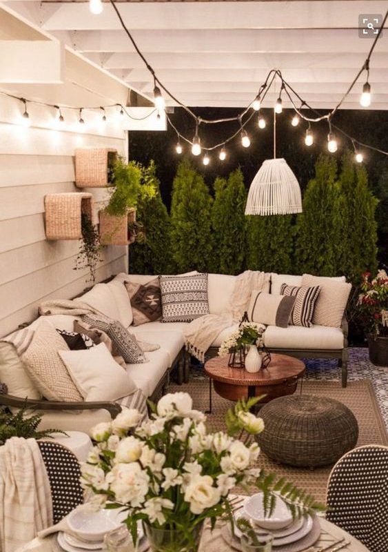 A boho patio with a large L shaped sofa and a coffee table next to it plus wicker ottomans