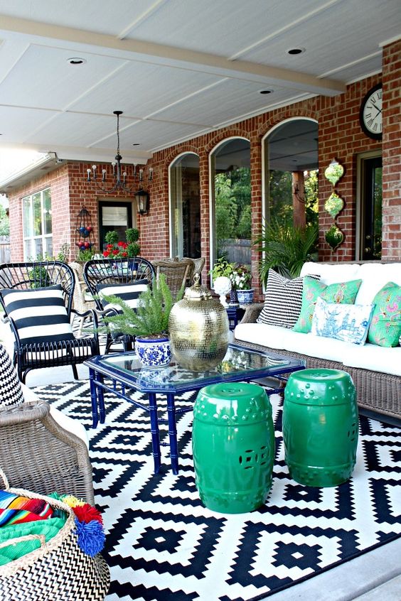 a super colorful patio done around a blue glass coffee table with various mismatching seating options