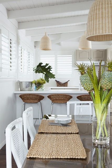 a tropical dining room with wicker lamps and stools in the breakfast zone plus some woven placemats