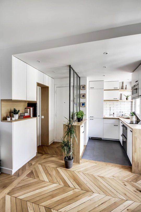 a small and welcoming open floor plan uniting the kitchen and entryway is done in white and light-colored wood