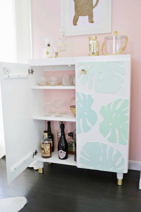 an IKEA Ivar cabinet turned into a stylish kid-proof home bar with dimensional monstera leaves and gilded legs