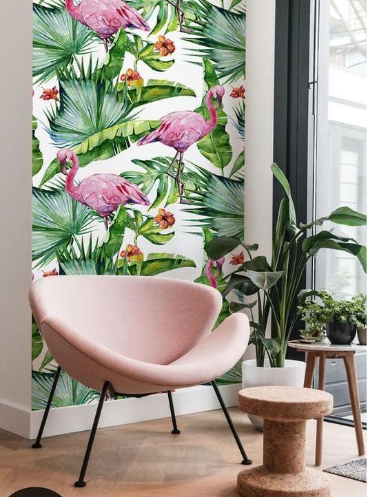 a cozy nook with pink flamingo print wallpaper, a blush chair, potted plants and a cork side table