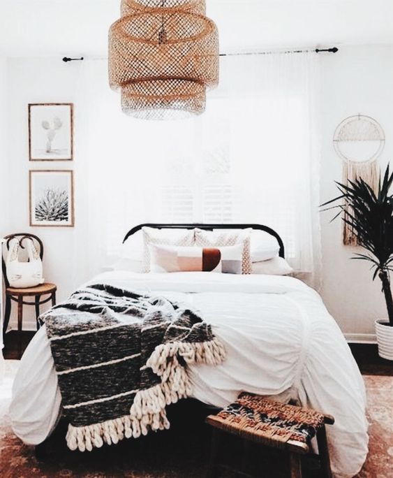 a welcoming boho bedroom with a large wicker lampshade over the bed that adds a boho feel to the space