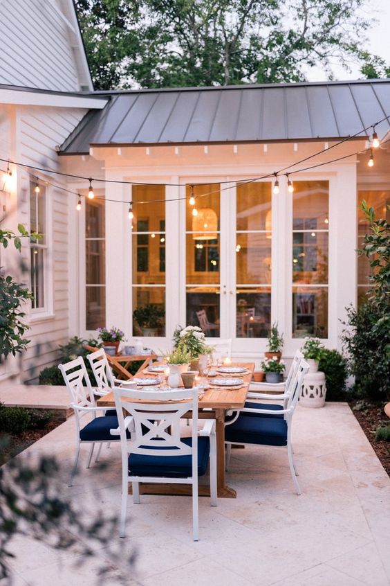 include a dining space into your patio with a table and white and navy chairs, spruce it up with potted plants