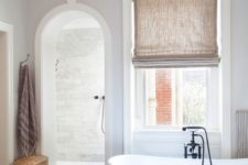 13 a contemporary bathroom with an arched doorway inviting to the shower space for more eye-catchiness