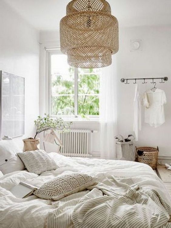 a welcoming neutral bedroom with a large wicker lamp over the bed that adds a natural feel to the space