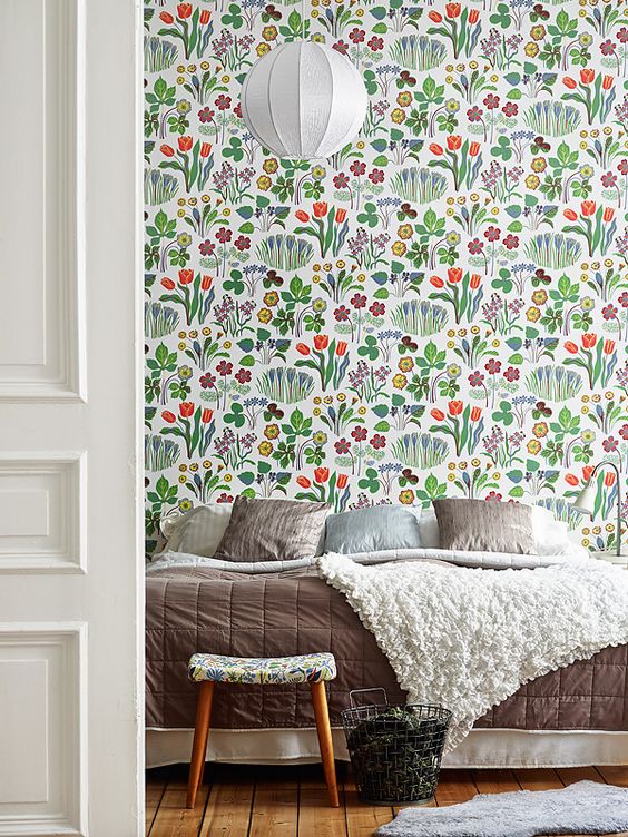 Cheerful bright floral wallpaper on the statement wall make the bedroom more welcoming and summer like