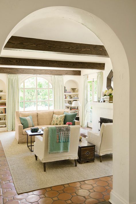 a charming living room with wooden beams and an arched doorway that set the tone in the space