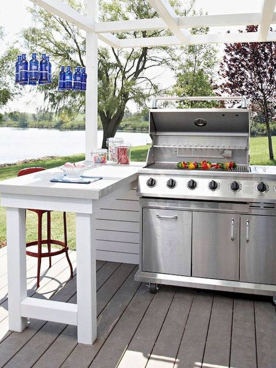 an outdoor grill plus some eating space and blue bottles hanging over it